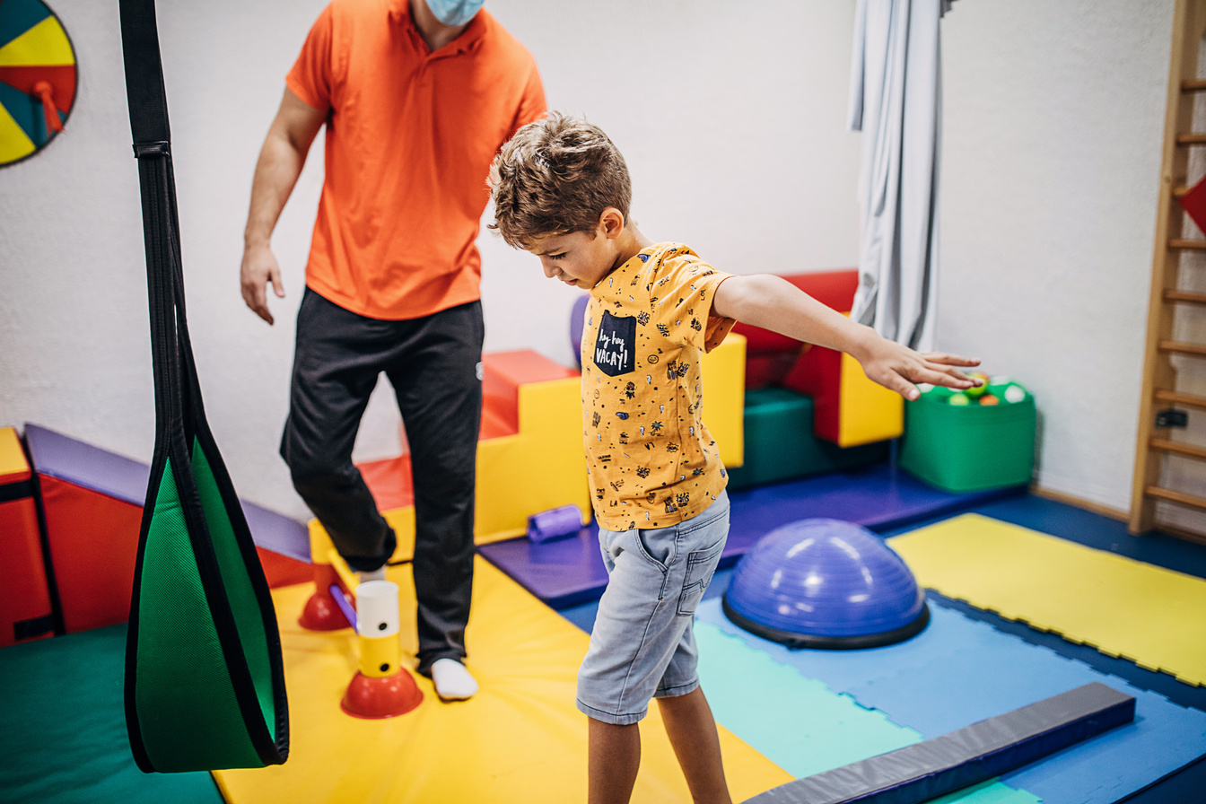Boy exercising with physical therapist in sensory room